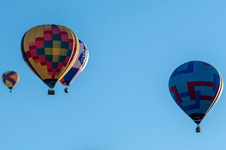 Four hot air balloons flying close to each other.