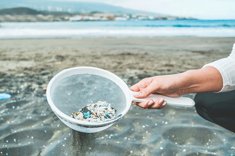 A person using a drainer to get microplastics out of the water