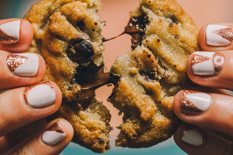 Image of hands pulling apart a warm chocolate chip cookie